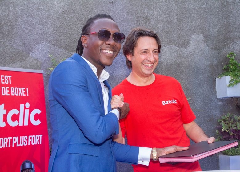 Image de Musique/Radio. Le rappeur béninois Vano Baby, déjà ambassadeur de la marque Celtiis Bénin, continue de s'étendre dans le monde du partenariat et de l'ambassadeurship en signant un nouveau contrat avec Betclic, une entreprise française spécialisée dans les paris sportifs, le poker en ligne et les courses hippiques. La signature officielle de ce partenariat a eu lieu le 25 octobre 2023 à la Centrale Company de Richard Flash en présence de professionnels des médias et d'autres acteurs clés. Maximiliano Monté, Directeur Général Afrique de BetClic, a exprimé sa satisfaction concernant ce partenariat, le qualifiant d'exceptionnel entre deux entités visionnaires, Vano Baby et Betclic. Selon lui, ce partenariat repose sur l'action, l'innovation, la créativité, et l'excellence. Il a salué le charisme, le talent et la passion de Vano Baby, soulignant que sa musique ne se limite pas à divertir, mais raconte des histoires et évoque des émotions. Vano Baby incarne l'esprit de l'audace, selon Monté. L'objectif de ce partenariat est de célébrer l'innovation, l'intégrité et le jeu responsable. La MOE CENCO-ECC a souligné que la confiance, le respect et la collaboration sont les fondements de ce partenariat, et que l'objectif commun est de repousser les limites, de créer une expérience unique et d'offrir des opportunités d'amusement exceptionnelles aux fans et clients. Toutefois, les termes du contrat n'ont pas été divulgués à la presse. Vano Baby, pour sa part, a exprimé sa gratitude envers Betclic pour l'avoir choisi comme ambassadeur. Il a promis de mettre tout en œuvre pour faire de ce partenariat une expérience exceptionnelle. Il a également souligné l'importance des paris sportifs au Bénin, en particulier parmi les jeunes, et a rappelé que Betclic est destiné aux personnes de 18 ans et plus, soulignant sa légalité. Hubert Micho, Directeur de développement de Betclic, a expliqué les démarches entreprises pour que Betclic puisse s'associer avec Vano Baby. Il a souligné que Betclic suit de près le rappeur depuis un certain temps et a exprimé sa satisfaction d'avoir réussi à concrétiser ce partenariat. Il a affirmé que Betclic vise à devenir le numéro 1 des paris sportifs au Bénin avec Vano comme ambassadeur, considérant cette collaboration comme le début d'une belle histoire. En ce qui concerne les règles légales d'accès à Betclic, Hubert Micho a souligné que les mineurs ne sont pas autorisés à utiliser la plateforme. Il a expliqué que pour garantir la vérification automatique de l'âge des joueurs, tout parieur ou utilisateur doit fournir une copie de sa carte d'identité, car il est impératif d'être majeur pour utiliser Betclic. Les joueurs non identifiés ne sont pas autorisés sur la plateforme. Ce partenariat entre Vano Baby et Betclic ouvre de nouvelles opportunités pour le rappeur béninois et renforce sa présence dans le monde du divertissement et des paris sportifs. Il souligne également l'importance croissante des paris sportifs au Bénin, en particulier parmi la jeunesse. La question qui se pose est de savoir comment ce partenariat évoluera et quel impact il aura sur le secteur des paris sportifs dans le pays.